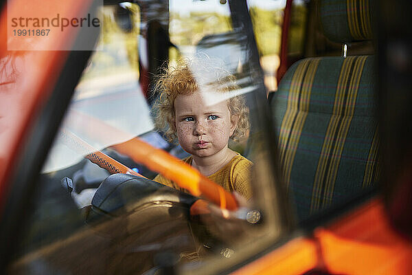 Innocent girl sitting on driver's seat of motor home