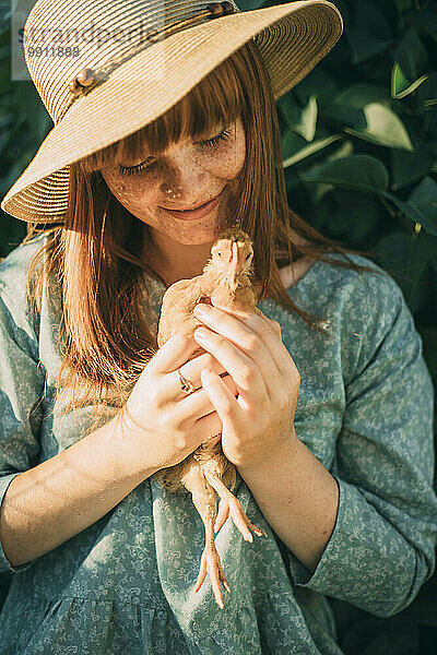 Junge Frau mit Sommersprossen hält Huhn