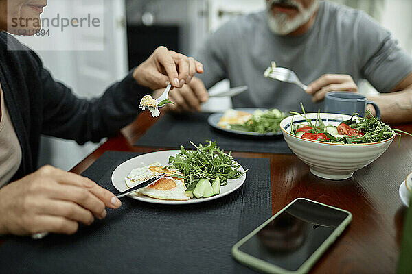 Couple eating fried eggs and salad for breakfast at home