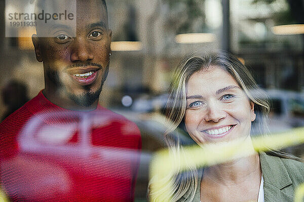 Lächelnde Geschäftskollegen hinter Glasfenster