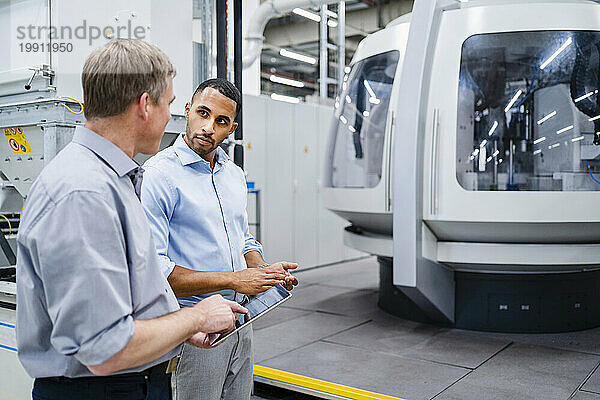Zwei Geschäftsleute treffen sich an einer modernen Maschine in einer Fabrik