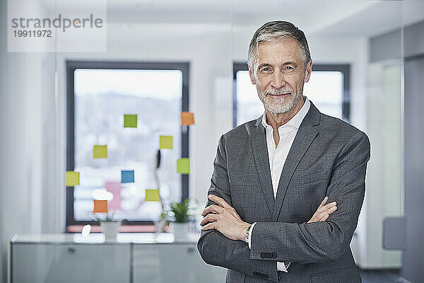 Smiling senior businessman standing with arms crossed