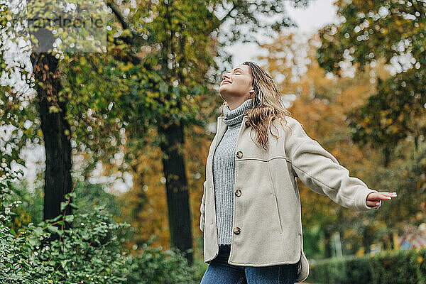 Sorglose junge Frau mit geschlossenen Augen im Herbstpark