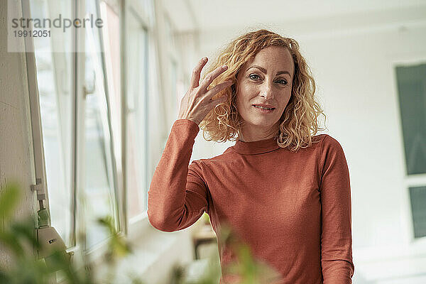 Lächelnde Geschäftsfrau mit blonden Haaren  die im Büro steht