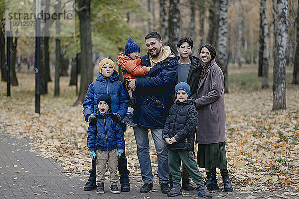 Glückliche Familie  die zusammen vor Bäumen im Park steht