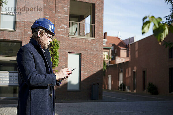 Architect using smart phone in front of buildings
