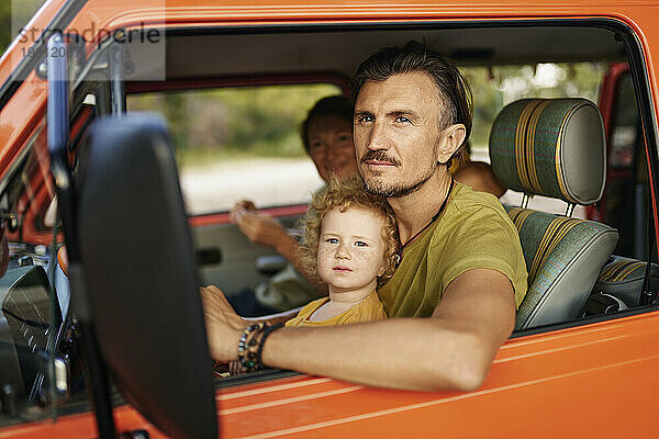 Eltern mit Tochter sitzen im Wohnwagen im Urlaub