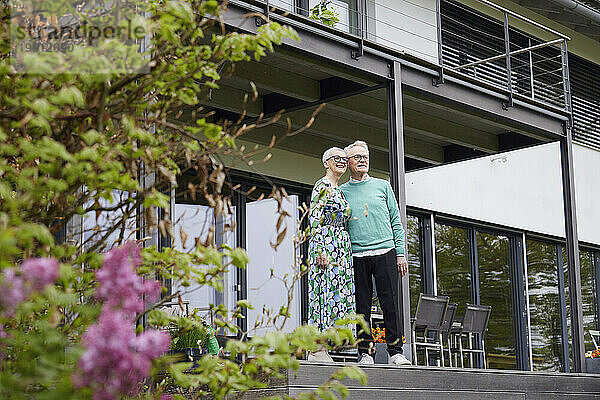 Älteres Paar steht vor seinem Haus