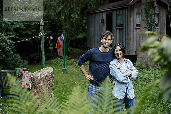 Lächelnder Mann steht mit Frau vor Blockhütte