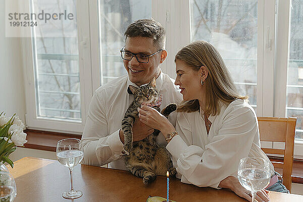 Young couple celebrating cat's birthday at home