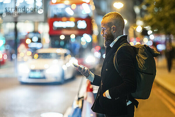 Mann mit der Hand in der Tasche benutzt Smartphone in der Stadt