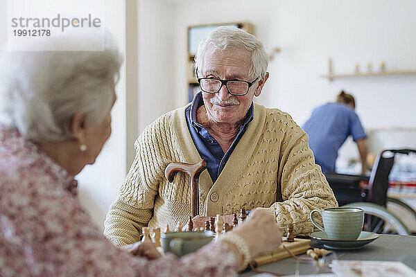 Lächelnder älterer Mann mit Frau am Tisch