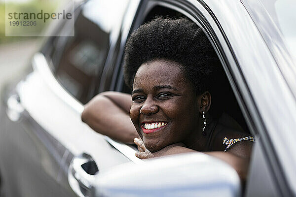 Lächelnde Frau lehnt am Fenster eines Autos