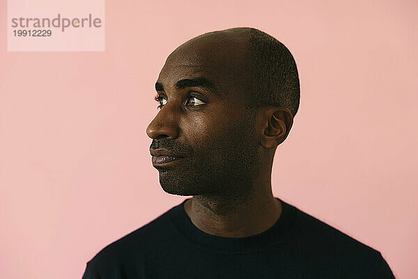 Man with shaved head against pink background