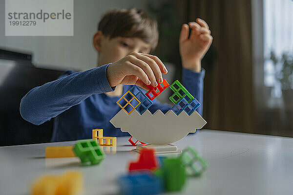 Elementary boy balancing toy blocks at home