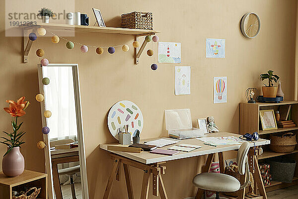 Mit Zeichnungen und Spiegel dekorierter Schreibtisch zu Hause