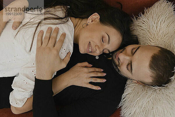 Loving couple lying down and embracing at home