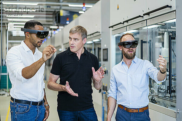 Zwei Techniker tragen Augmented-Reality-Brillen in einer Fabrik und interagieren mit Kollegen