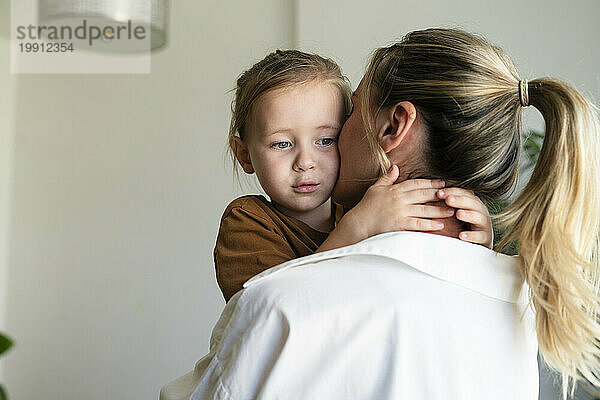 Blonde Frau umarmt und küsst Sohn zu Hause