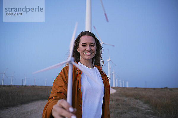 Glückliche Frau hält Windturbinenmodell auf dem Feld
