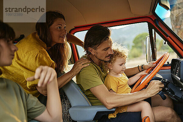 Reifer Mann sitzt mit Familie im Wohnwagen im Urlaub