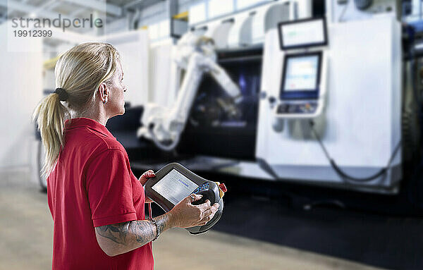 Techniker bedient Roboterarm und Maschine über Tablet-PC in der Fabrik
