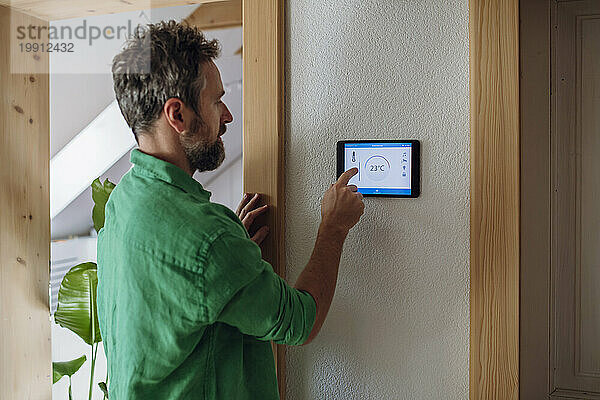 Mann regelt die Temperatur zu Hause auf einem Tablet-PC