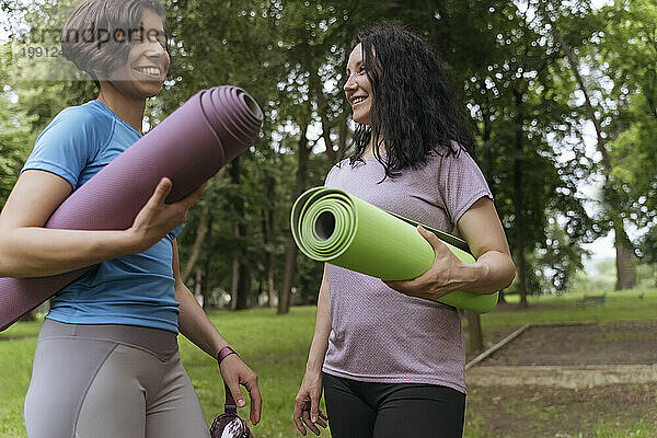 Aktive Frauen mit Gymnastikmatten stehen im Park