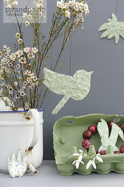 Studio shot of DIY Easter decorations and blooming flowers in enamel jug