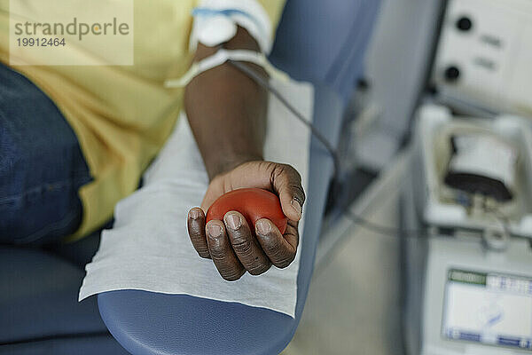 Hand of man squeezing ball in hand at blood donation center