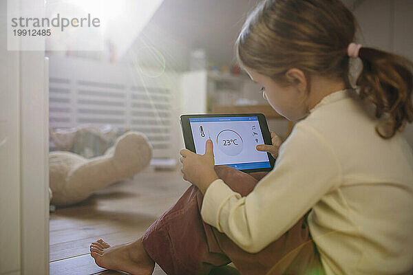 Mädchen passt die Temperatur über die Hausautomations-App auf dem Tablet-PC an
