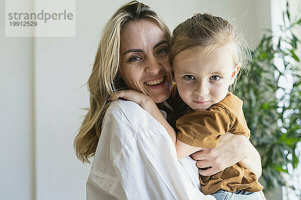 Glückliche blonde Mutter umarmt Jungen zu Hause