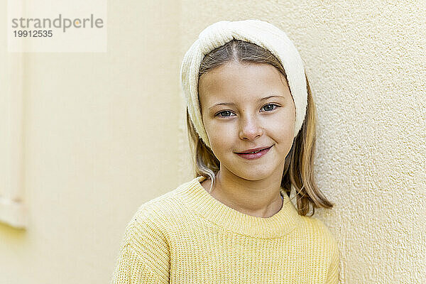 Smiling girl wearing headband in front of wall