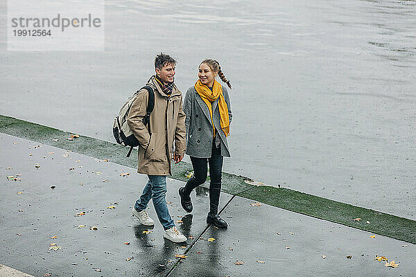 Smiling couple walking together near river