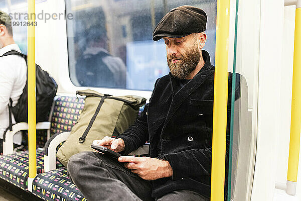 Mann benutzt Smartphone im Zug