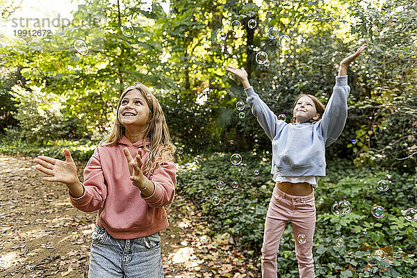 Lächelnde Mädchen spielen mit Seifenblasen im Park