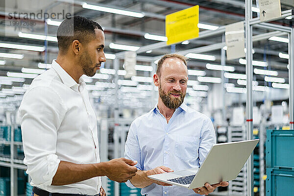 Zwei Geschäftsleute mit Laptop bei einem Treffen in einer Fabrik