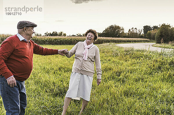 Fröhliches älteres Paar genießt und tanzt auf dem Feld