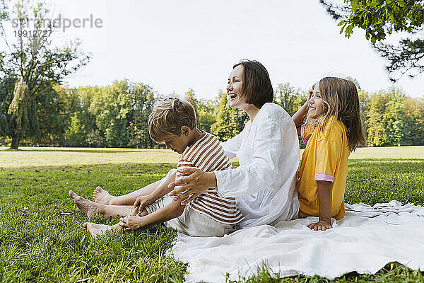 Glückliche Frau mit Sohn und Tochter  die auf einer Decke im Park sitzen