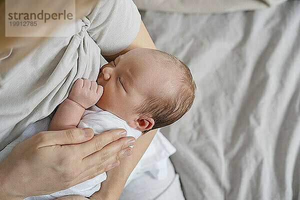 Woman breastfeeding newborn son in arms