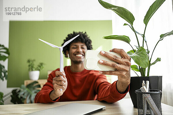 Freiberufler macht Selfie mit Windkraftanlage per Smartphone im Heimbüro