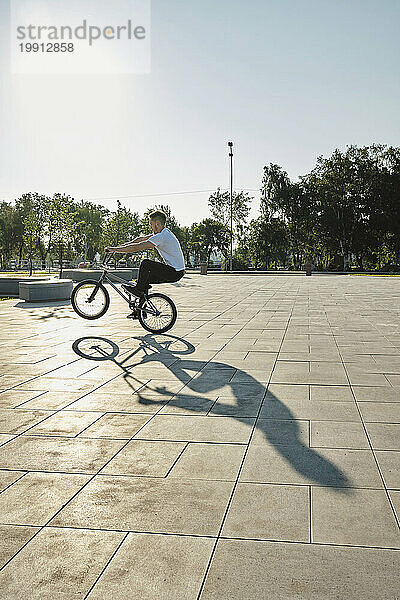 Mann fährt an sonnigem Tag BMX-Fahrrad im Park