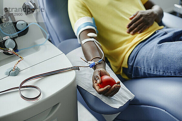 Man holding soft ball and donating blood at center
