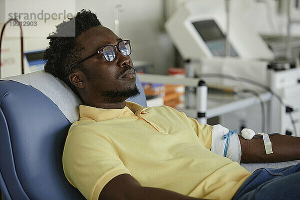 Mann mit Brille spendet Blut