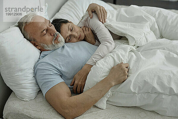 Couple cuddling each other during sleep in bed