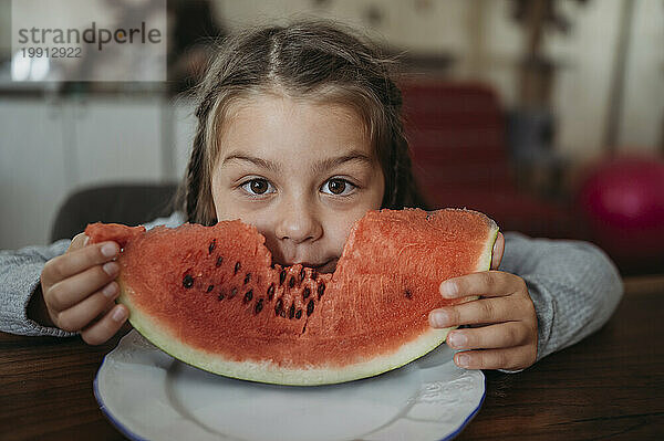 Mädchen isst zu Hause ein Stück Wassermelone