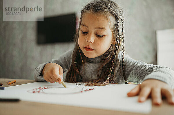 Mädchen mit geflochtenen Haaren zeichnet zu Hause mit Buntstift