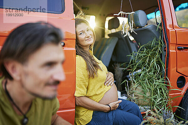 Schwangere Frau sitzt im Wohnwagen bei einem männlichen Freund im Urlaub