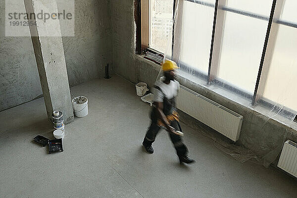 Construction worker walking near window at site