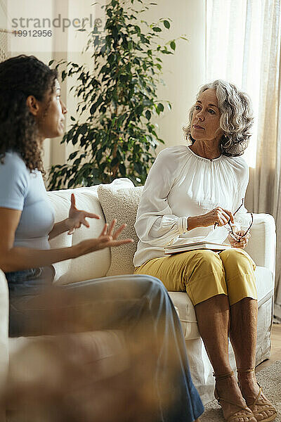 Frau gestikuliert und spricht mit dem Therapeuten zu Hause über psychische Probleme
